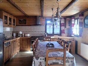 Eine rustikale Küche mit Holzsäulen, einer zentralen Kochinsel mit Stühlen, einem Herd und einer Hängelampe.