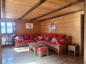 Ein gemütliches Holzhaus-Interieur mit einem großen roten Sofa, Holztischen und einem Essbereich.