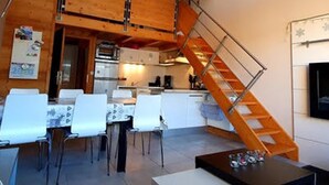 Et moderne interiør med spiseplads, køkken og trappe.