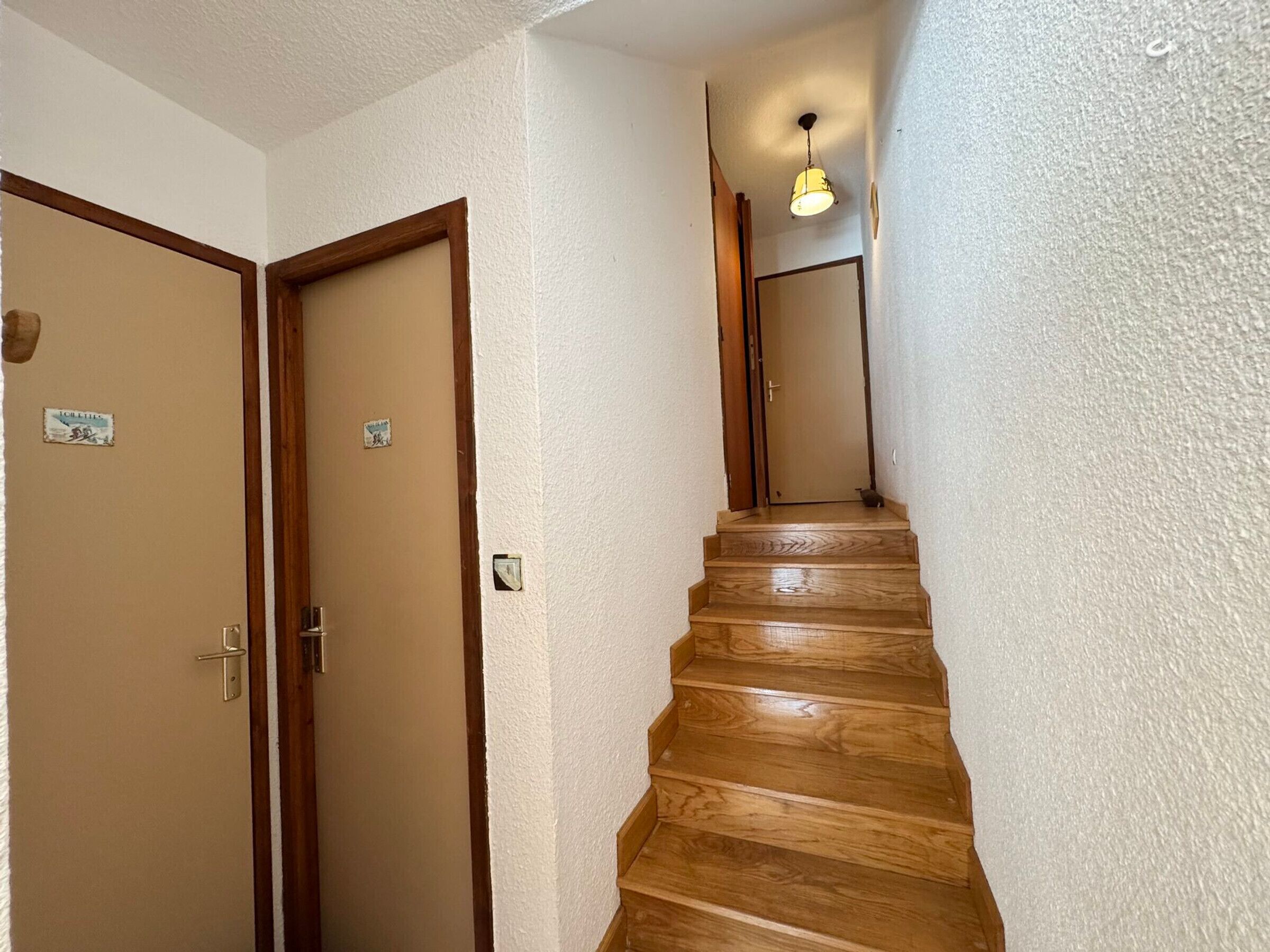 Una escalera de madera que conduce a una puerta con una lámpara encima.