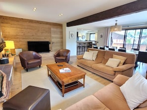A living room with a sofa, two armchairs, a coffee table, and a TV. - Renovated family chalet, near center, sleeps 12, parking, WiFi (Les Gets)