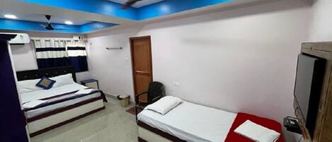A hotel room with two beds, a TV, a ceiling fan, and a red chair.