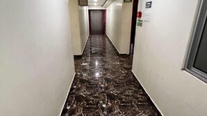 A hallway with white walls, a marble floor, and a ceiling light. - Elite Square  (Port Blair)