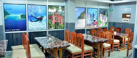 A restaurant with wooden tables and chairs, large windows with scenic views, and a 'No Smoking' sign.