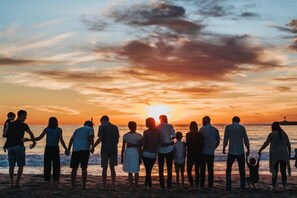 A group of people standing on a beach during sunset. - DisneyMansion by AmericanVacationLiving 11Br - 30p (Davenport)