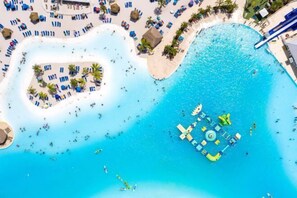 An aerial view of a resort with a large central pool, multiple smaller pools, and a variety of sun loungers and umbrellas. - DisneyMansion by AmericanVacationLiving 11Br - 30p (Davenport)