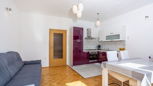 A compact living space with a kitchenette, a grey sofa, and a dining table. - Charming Senj by Villas Guide (Senj)