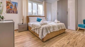 A modern bedroom with a large bed, a nightstand, a wardrobe, and a chair.