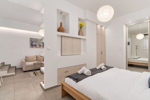 Ett modernt sovrum med en stor säng, en inbyggd garderob, en sittgrupp med en soffa och ett litet bord.