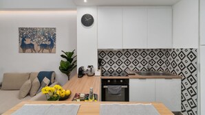 Een moderne keuken met een klok, een decoratieve spatwand en een eethoek met een plant en bloemen.