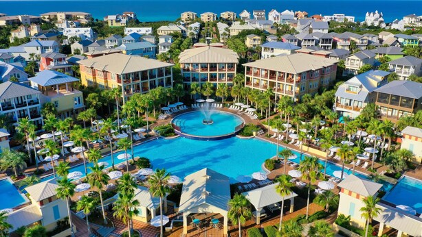 Een resort met een centraal zwembad, meerdere gebouwen en uitzicht op de oceaan.