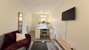 Ein gemütlicher Raum mit Bett, Schreibtisch, Stuhl und einem an der Wand befestigten Fernseher.