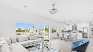 A modern living room with a sofa, a glass coffee table, and a blue chair. - Saltwater Social ~ Game Room ~ Pool ~ Dock ~ Views (Marathon)