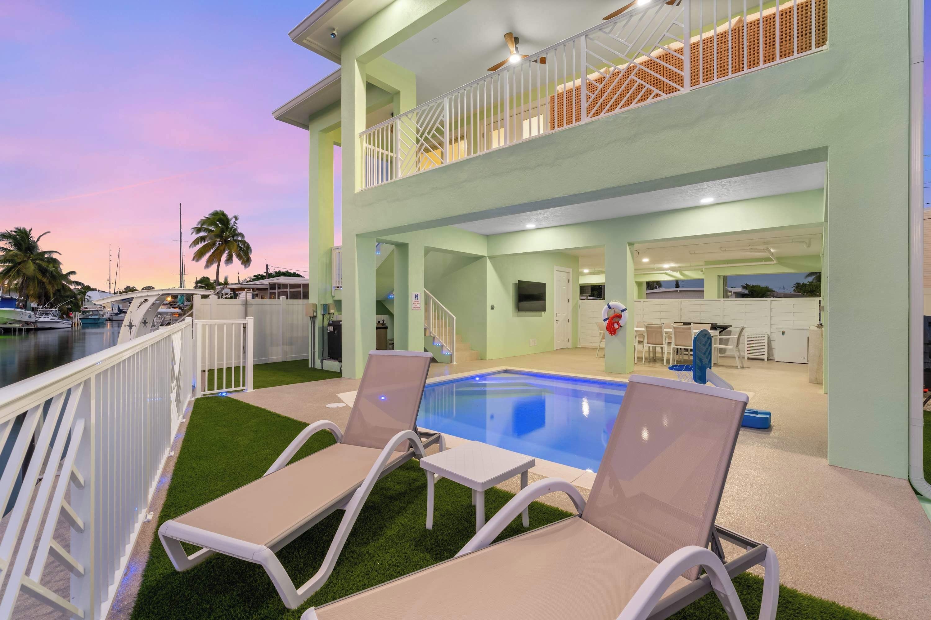 A pool area with lounge chairs and a staircase leading to an upper level.