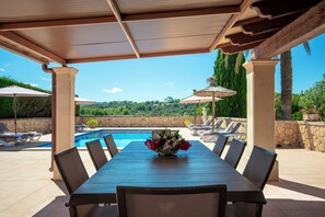 A covered outdoor dining area with a pool in the background. - Exclusive Mallorcan finca with new house, pool and views of the countryside (PM)