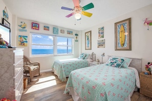 A bedroom with two beds, a ceiling fan, and a large window with a view of the ocean. - Oceanfront 2BR-Perfect Beach View Balcony (Satellite Beach)
