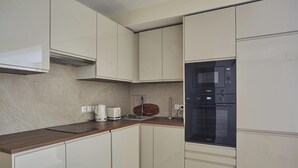 A modern kitchen with white cabinets, a wooden countertop, a built-in microwave, and a coffee maker. - Elegant Apartment St Germain des prés Luxembourg Park (Paris)