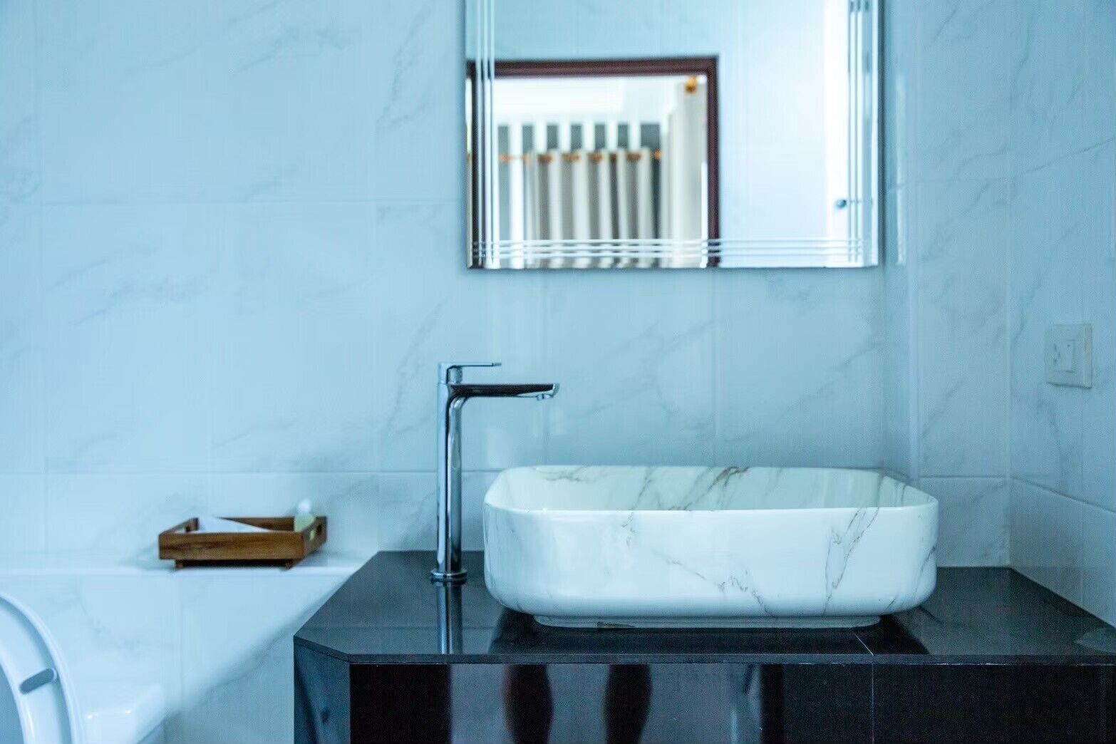 A bathroom with a white marble sink, a chrome faucet, and a mirror above it.
