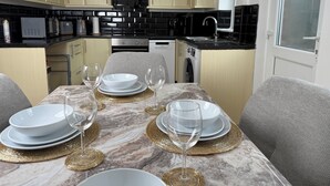 A modern kitchen with light wood cabinets, a black countertop, and a dining area set with white plates and gold placemats. - Urban Calm – Spacious 3-Bed Home with Free Parking
• Self Check-In (Rawmarsh)