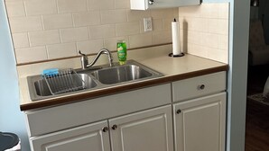 Una cucina con mobili bianchi, un piano di lavoro in legno, un lavello in acciaio inossidabile e un porta asciugamani di carta.
