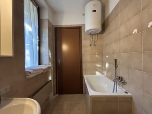 A bathroom with a bathtub, a shower, and a window with curtains. - Graziella 1 Apartment with a View of the Lake (Germignaga)