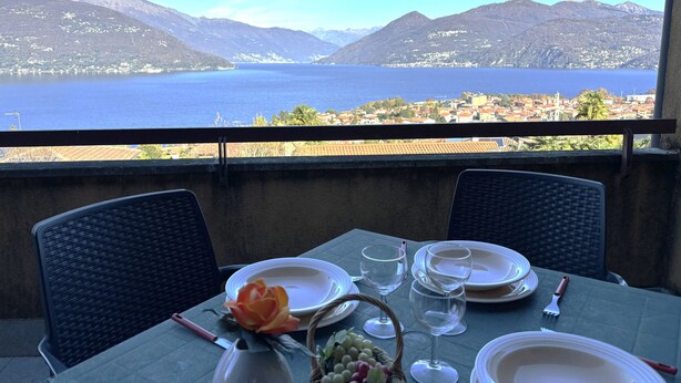 Mesa posta para refeição, com vista para um lago e montanhas.