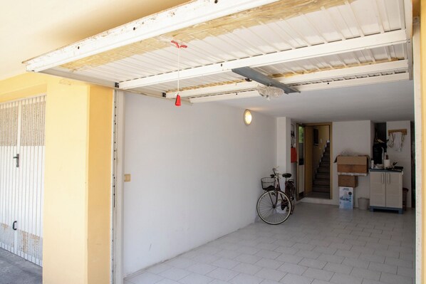 A garage with a bicycle, a staircase leading to a second floor, and a small kitchenette area. - Casa della Zia (Marotta)