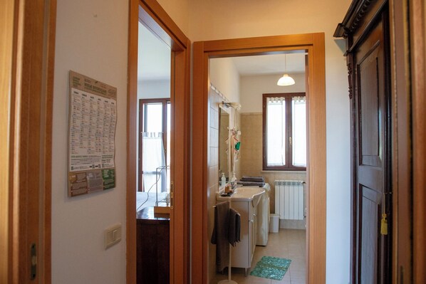 A narrow hallway leading to a bathroom with a sink, mirror, and towel rack. - Casa della Zia (Marotta)