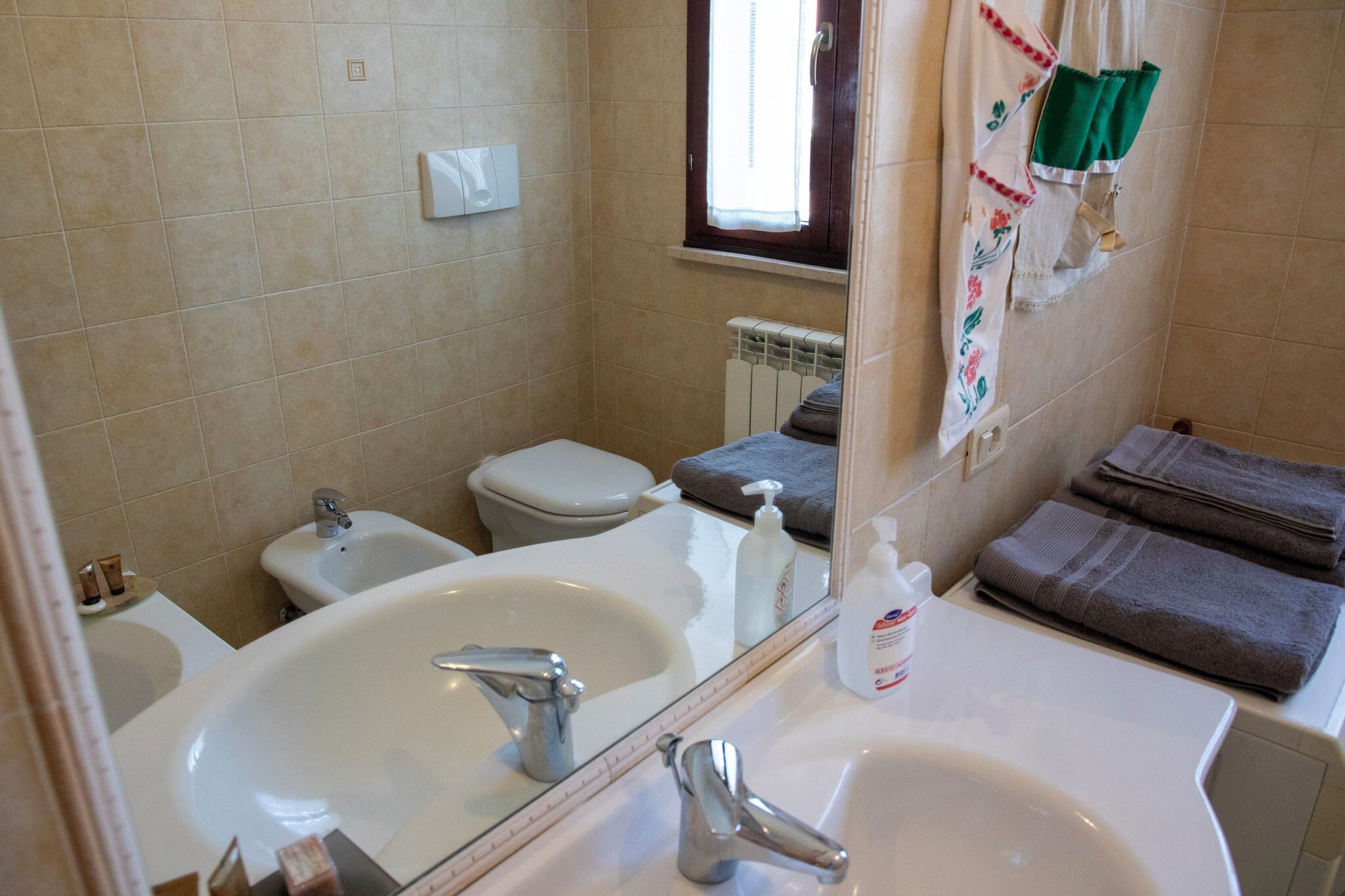 A bathroom with a sink, bidet, toilet, and a window.
