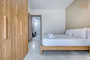 Un dormitorio con un armario de madera, una cama con ropa de cama blanca y vistas a otra habitación.