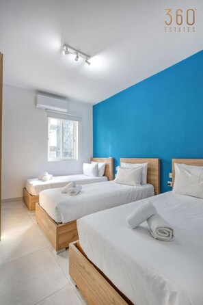 A hotel room with two beds, a large window, and a blue accent wall. - Spacious Paceville Getaway near Beach & Schools! (St. Julian`s)