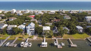 An aerial view of a coastal residential area with houses, a marina, and a pier.