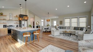 Amplia sala de estar con cocina, comedor y zona de estar con sofá y sillones.