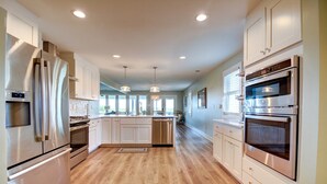 A modern kitchen with stainless steel appliances, a central island, and pendant lighting. - Explore Surf City from this spacious 6-bedroom, canal-front home, perfect for families. (Surf City)