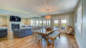 A spacious living area with a wooden dining table, comfortable seating, a fireplace, and a large TV. - Explore Surf City from this spacious 6-bedroom, canal-front home, perfect for families. (Surf City)