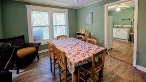 A dining area with a table set for four, wooden chairs, a ceiling fan, and a view of a kitchen through an open doorway. - 3BR House with BBQ & Fire pit, Bryson City (Bryson City)