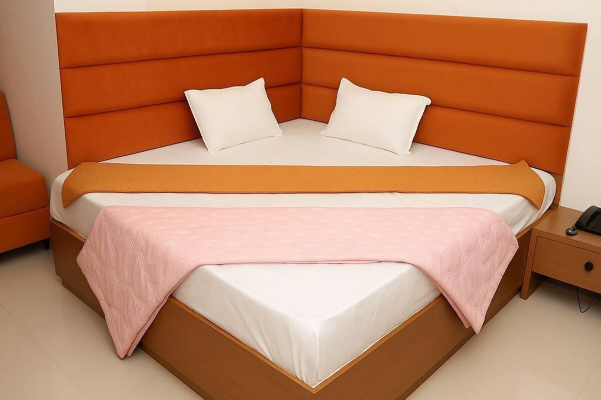 A modern bedroom with a large bed, a bedside table, and a wall-mounted light.