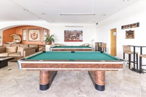 Une table de billard dans une pièce où se trouvent un canapé et une plante en pot.