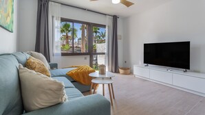 En moderne stue med sofa, fjernsyn og loftventilator.
