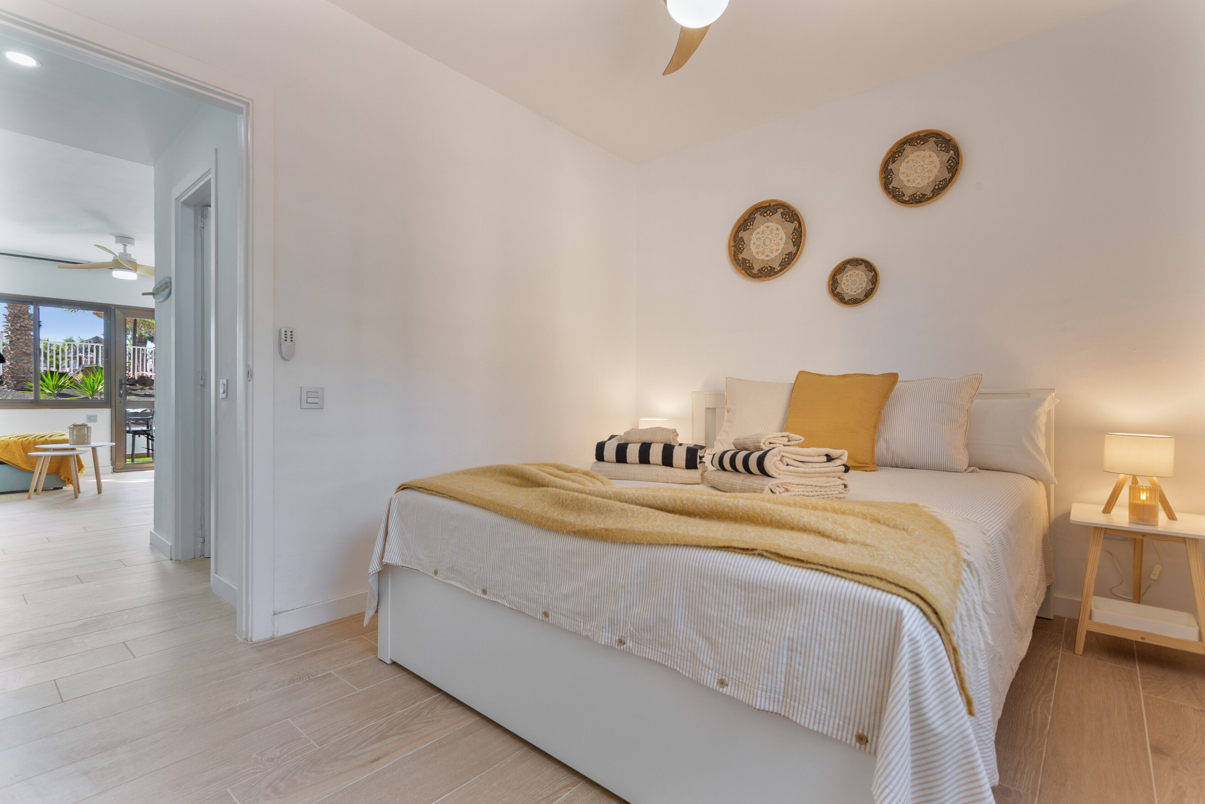 Un dormitorio moderno con una cama grande, una mesita de noche con lámpara y paneles decorativos en la pared.