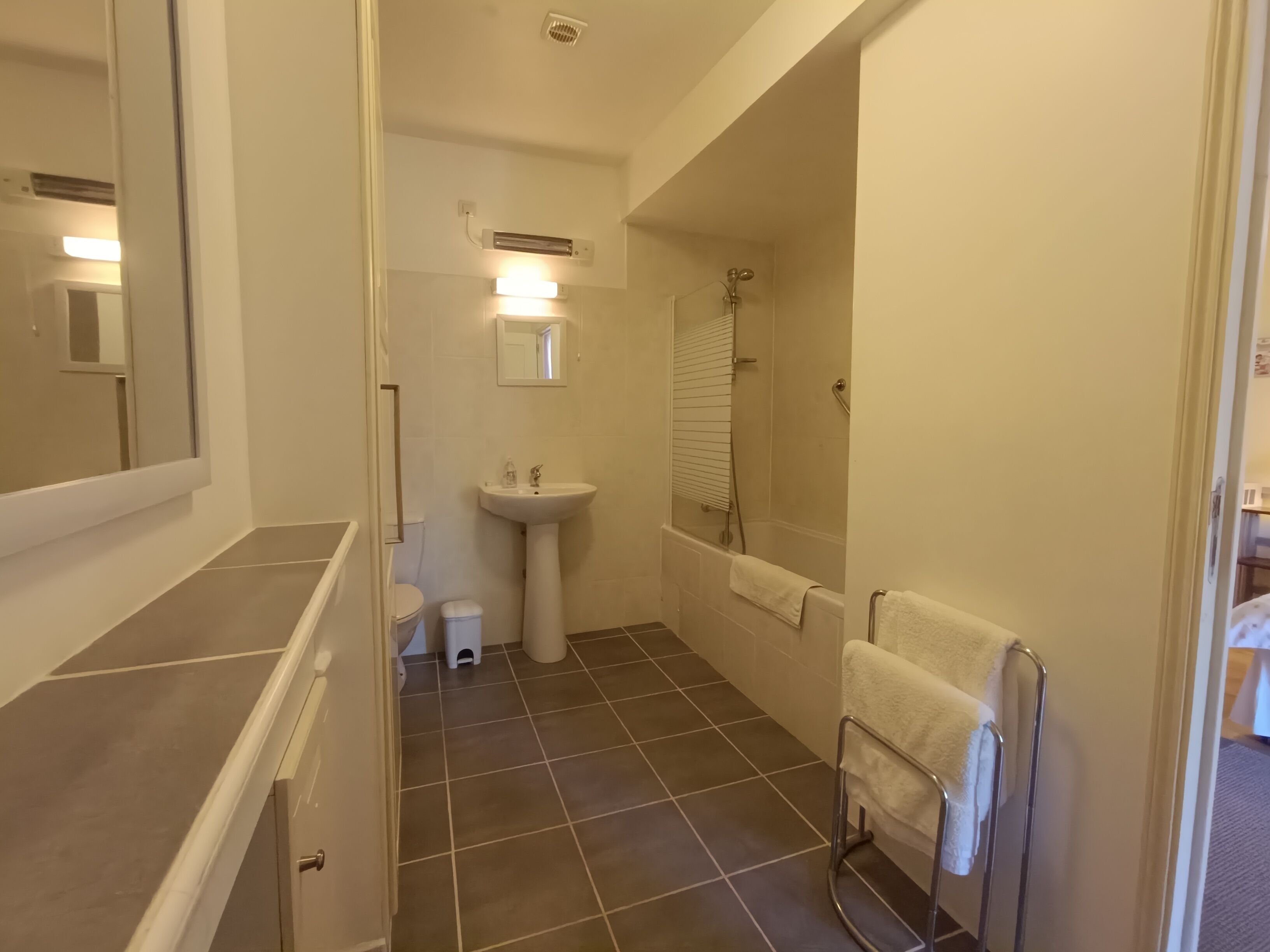 A bathroom with a sink, mirror, and shower.