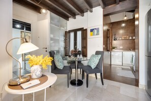A modern kitchen with a dining area, featuring a round table, chairs, a lamp, and a vase with yellow flowers. - Apartment 'Lovegranada Centro Ático Montalban' with Private Terrace, Wi-Fi and Air Conditioning (Granada)