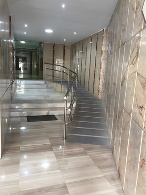 Eine moderne Hotelhalle mit einer Marmortreppe, Glastrennungen und einem polierten Boden.