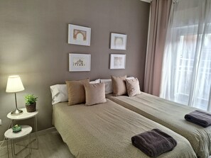 Ein Hotelzimmer mit zwei Betten, einem kleinen Tisch mit einer Lampe und gerahmten Bildern an der Wand.