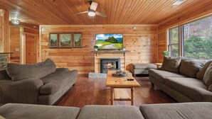 A cozy log cabin interior with a fireplace, wooden walls, and a television. - 10.3 Mi to Dollywood・Cozy Cabin Stay・Hot Tub・Games (Sevierville)