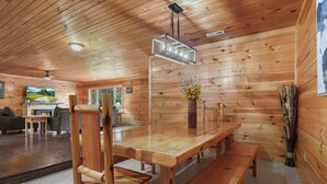 A wooden interior with a dining table, benches, a TV, and a fireplace. - 10.3 Mi to Dollywood・Cozy Cabin Stay・Hot Tub・Games (Sevierville)