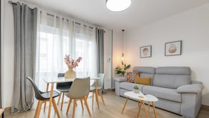 A modern living room with a grey sofa, a dining table with chairs, and a small side table. - Apartment 'Apartamento Canasteros 12 Centro' with Balcony, Wi-Fi and Air Conditioning (Granada)