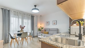 A modern kitchen with a granite countertop, stainless steel sink, and a dining area with a table and chairs. - Apartment 'Apartamento Canasteros 12 Centro' with Balcony, Wi-Fi and Air Conditioning (Granada)