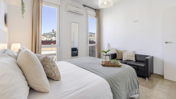Une chambre à coucher avec un lit, un canapé, une fenêtre et une porte.