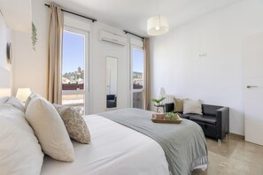Ein Schlafzimmer mit Bett, Sofa, Fenster und Tür.